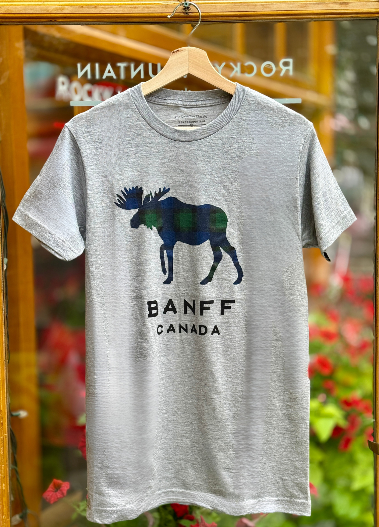 Grey t-shirt with moose graphic and 'Banff Canada' text on a hanger.