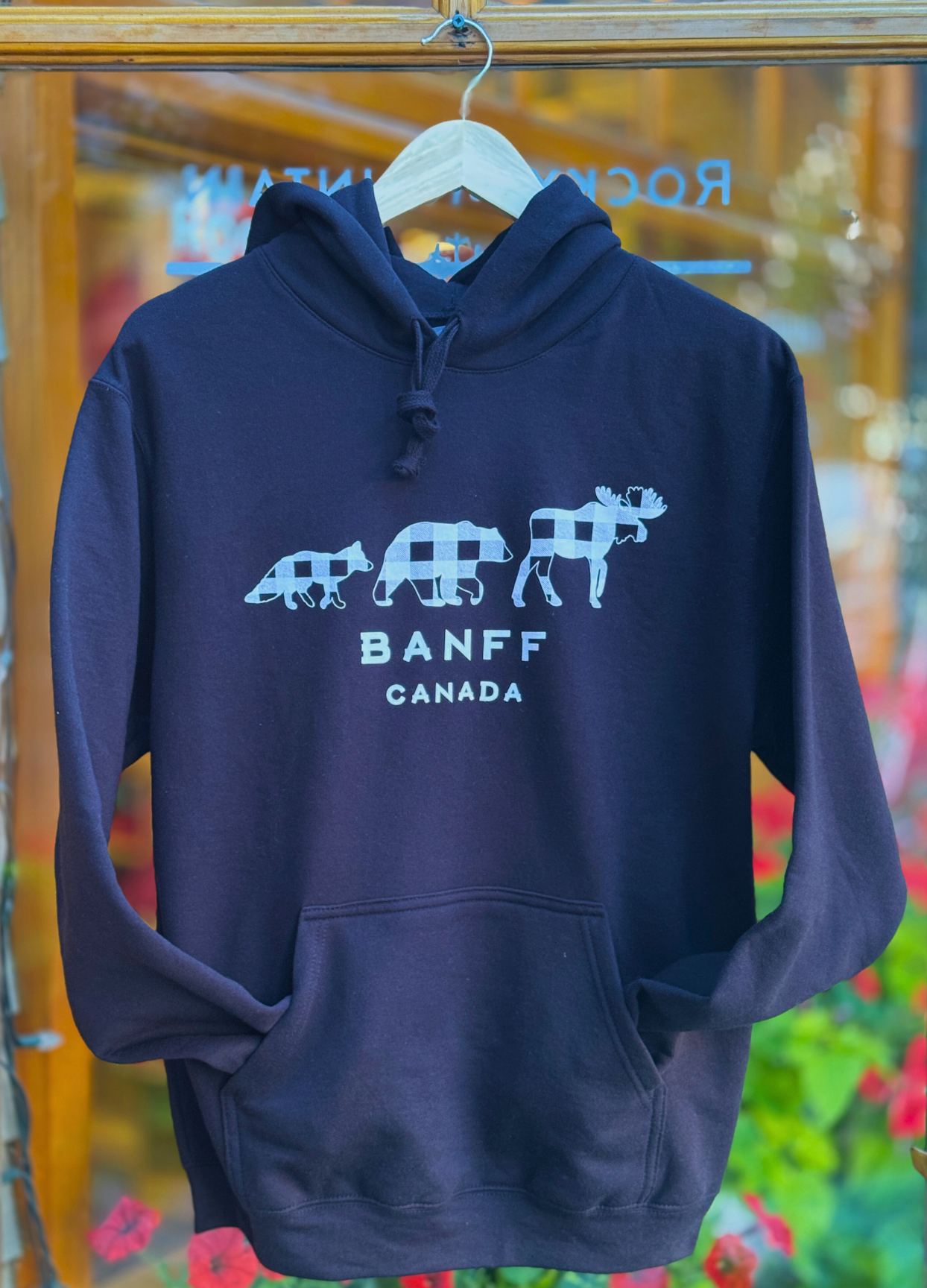Black hoodie with white graphic design on a hanger against a colorful background