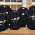 Black kids hoodies with 'Banff Canada' print on a wooden table.