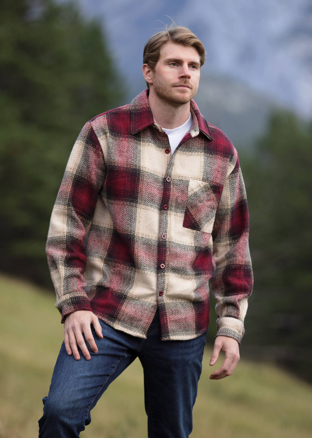 A person wearing a long-sleeved burgundy and beige plaid flannel shacket with a single breast pocket, button cuff, and V-silhouette.