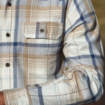 Close-up of a plaid flannel shirt with a focus on the collar and chest pocket.