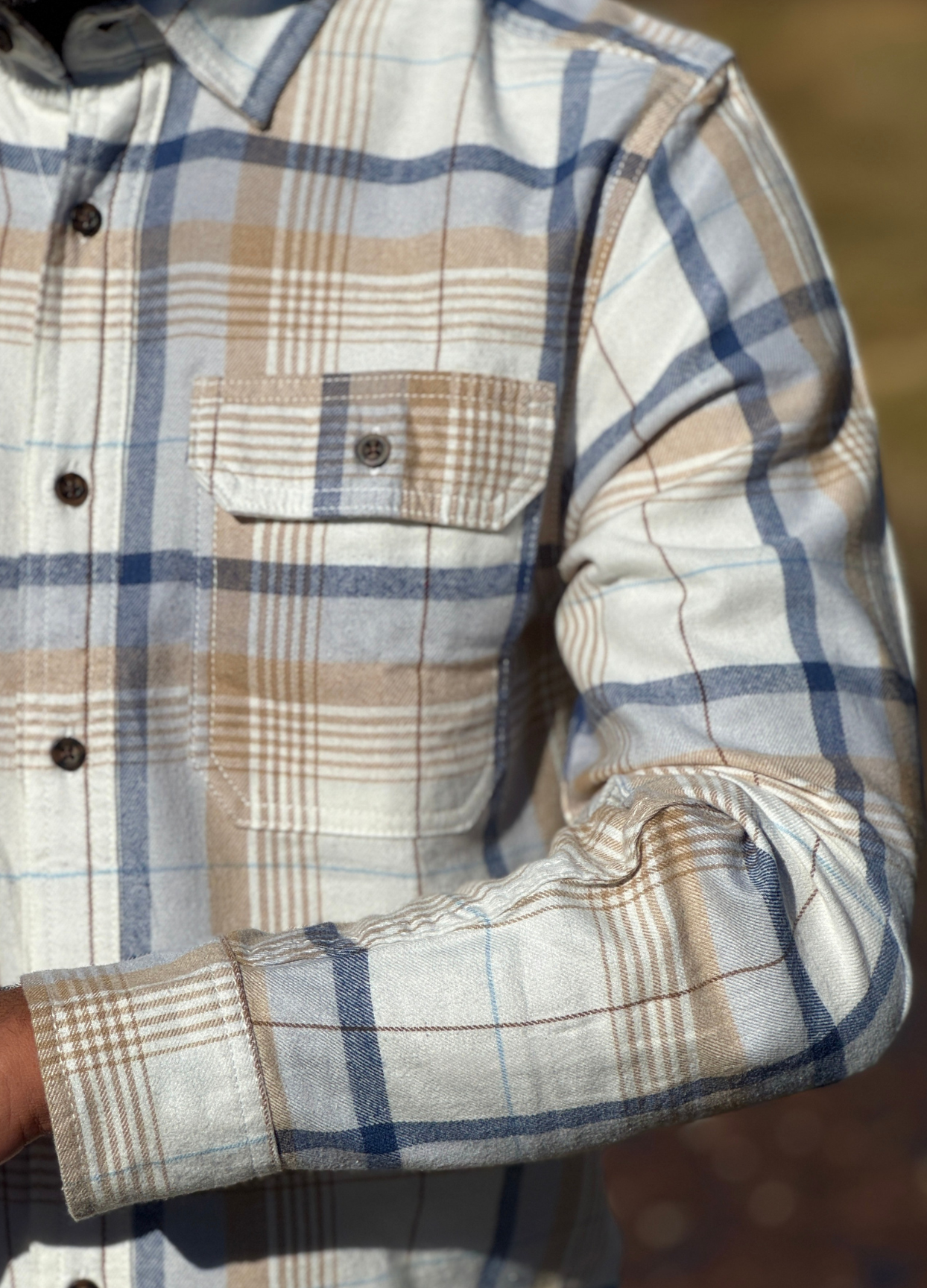 Close-up of a plaid flannel shirt with a focus on the collar and chest pocket.