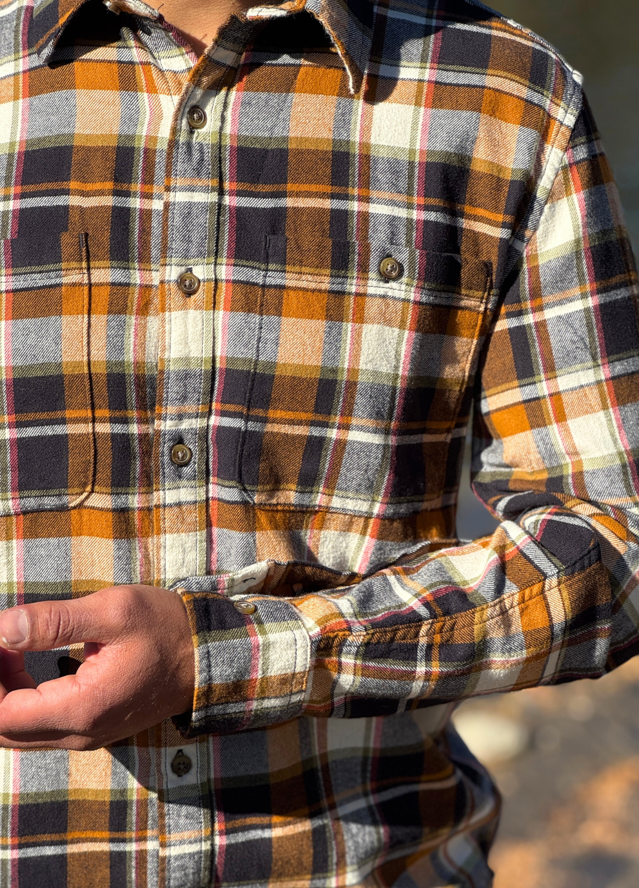Close-up of a person wearing a plaid flannel shirt with a blurred background
