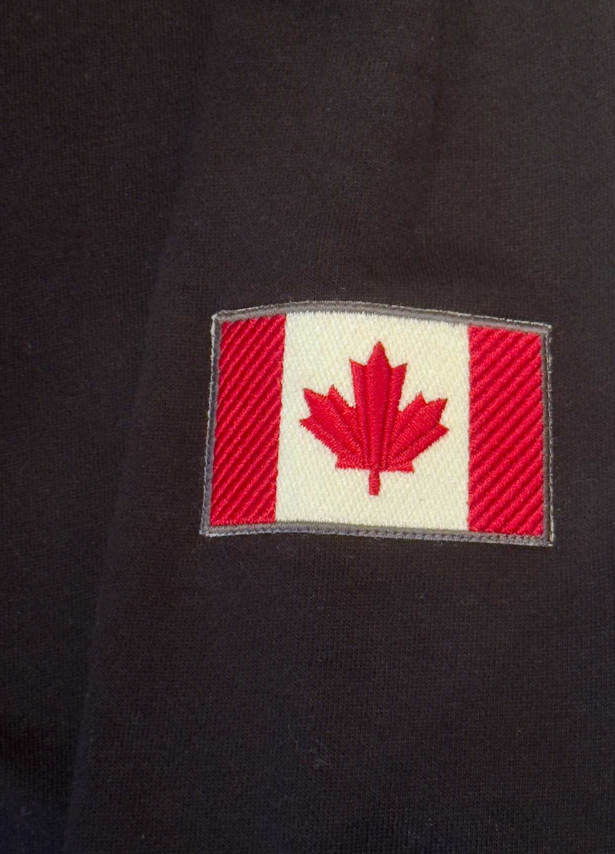 Canadian flag patch on black 3 button polo sleeve