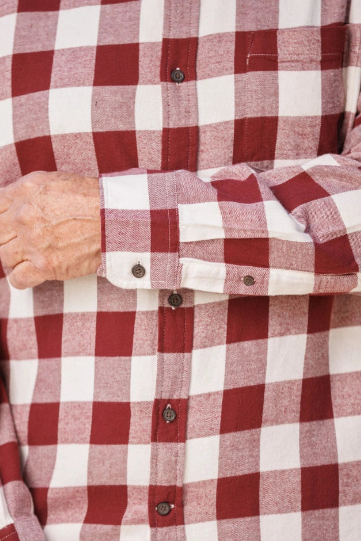 Close up of a burgundy and white buffalo check flannel shirt. Highlighting the button on the cuff.