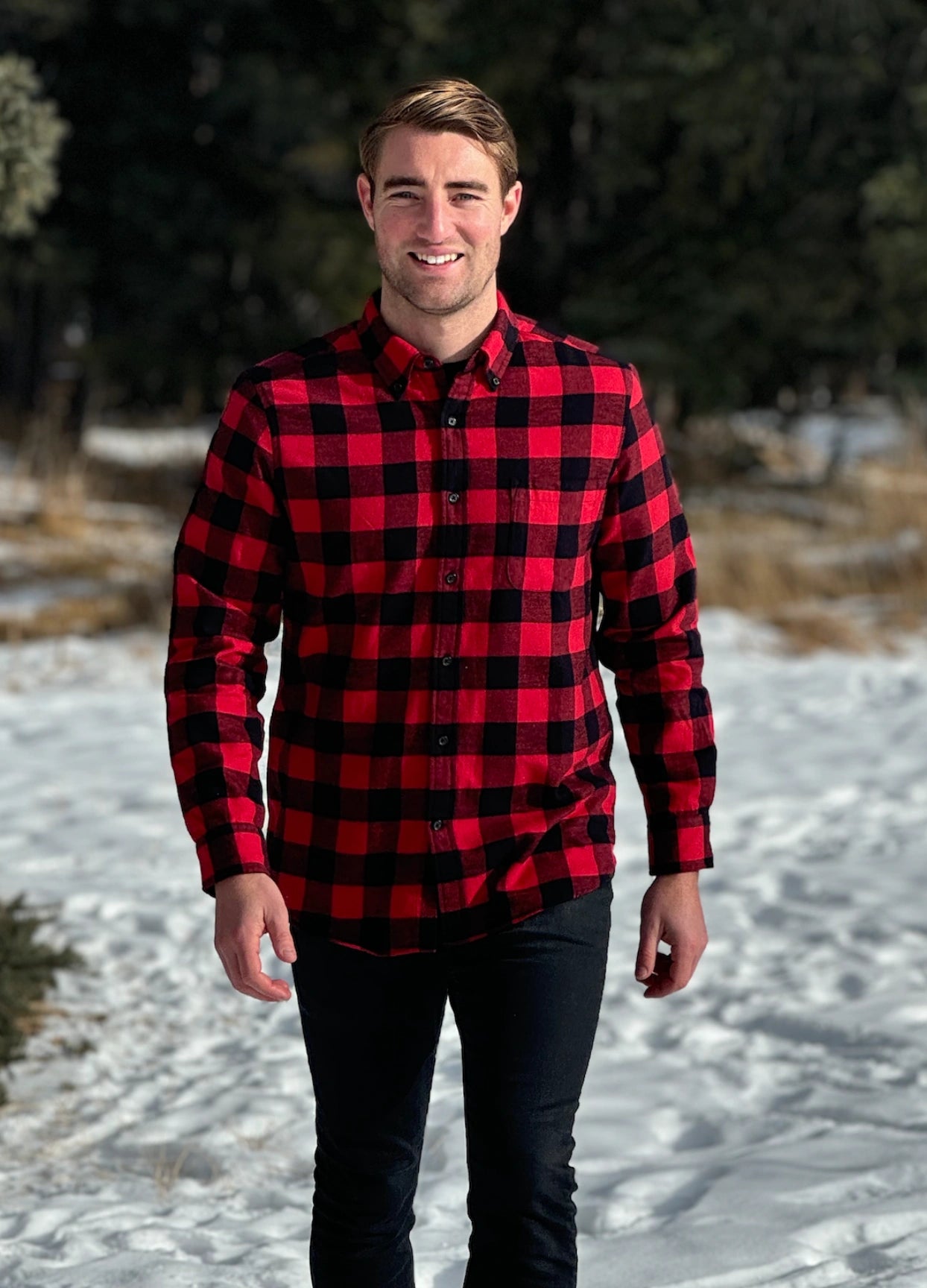 A man wearing a classic Canadian red and black buffalo check button-down shirt with a single pocket on the chest.