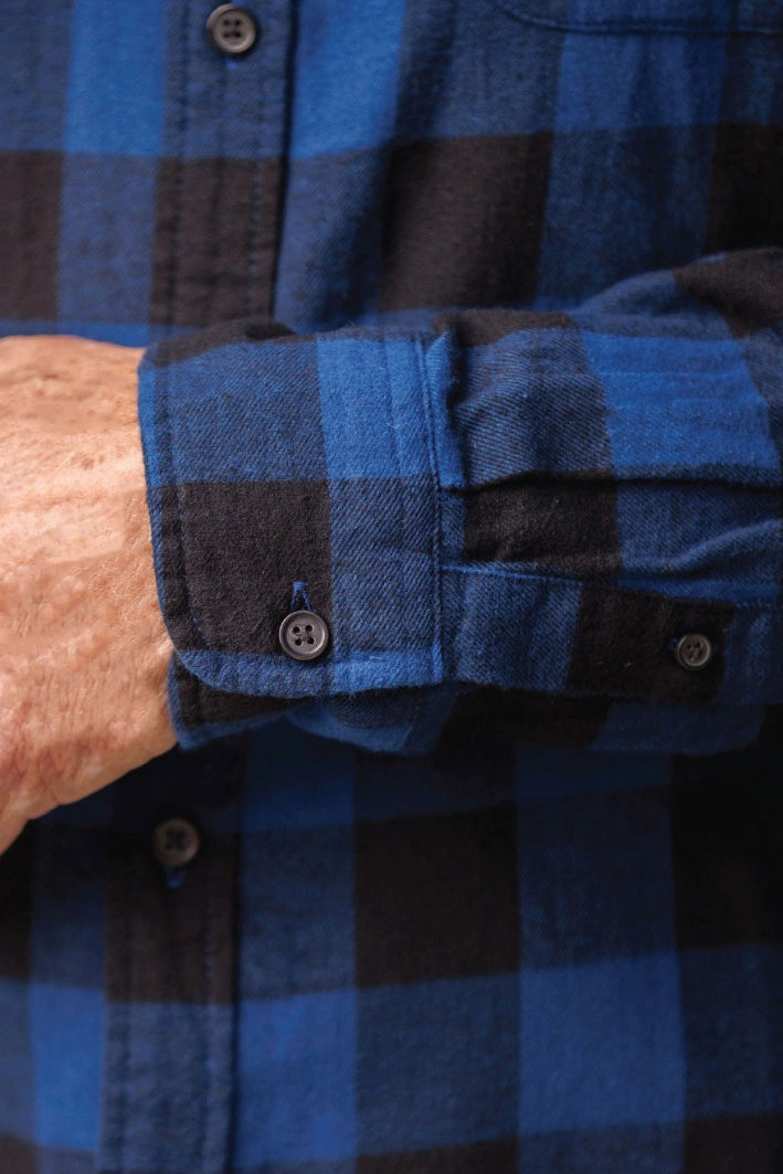Close up of the cuff of long-sleeved marine blue and black buffalo check flannel shirt.
