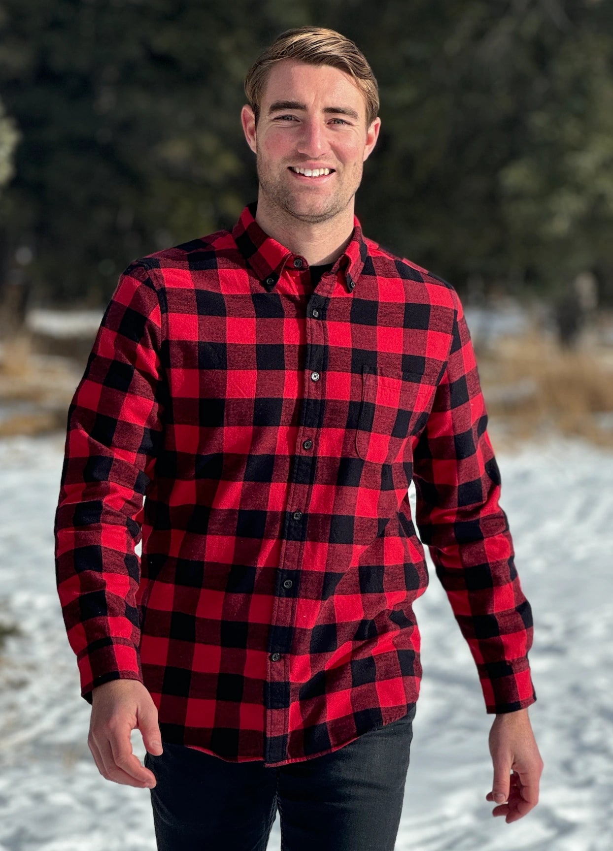 A man wearing a classic Canadian red and black buffalo check button-down shirt with a single pocket on the chest.