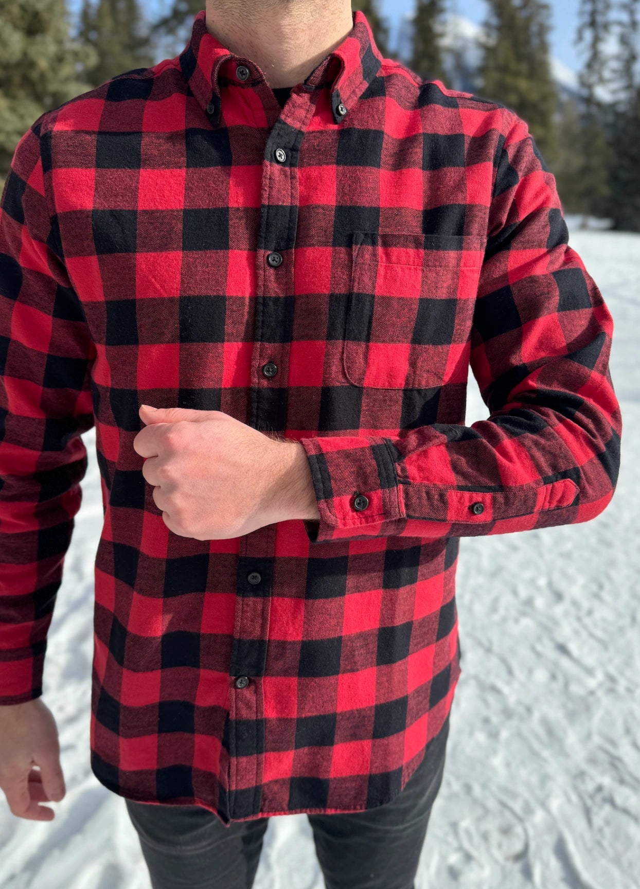 A man wearing a classic Canadian red and black buffalo check button-down shirt with a single pocket on the chest.