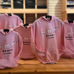Pink hoodies with 'Banff Canada' logo on a wooden table
