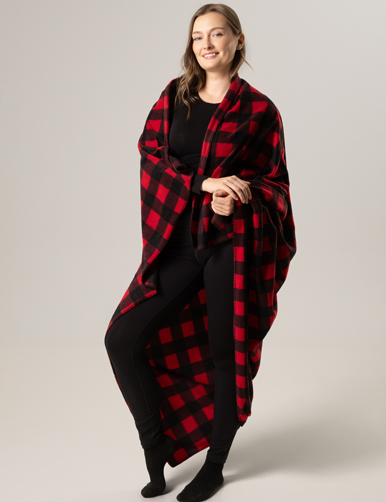 Woman wearing a red and black buffalo check blanket against a plain background