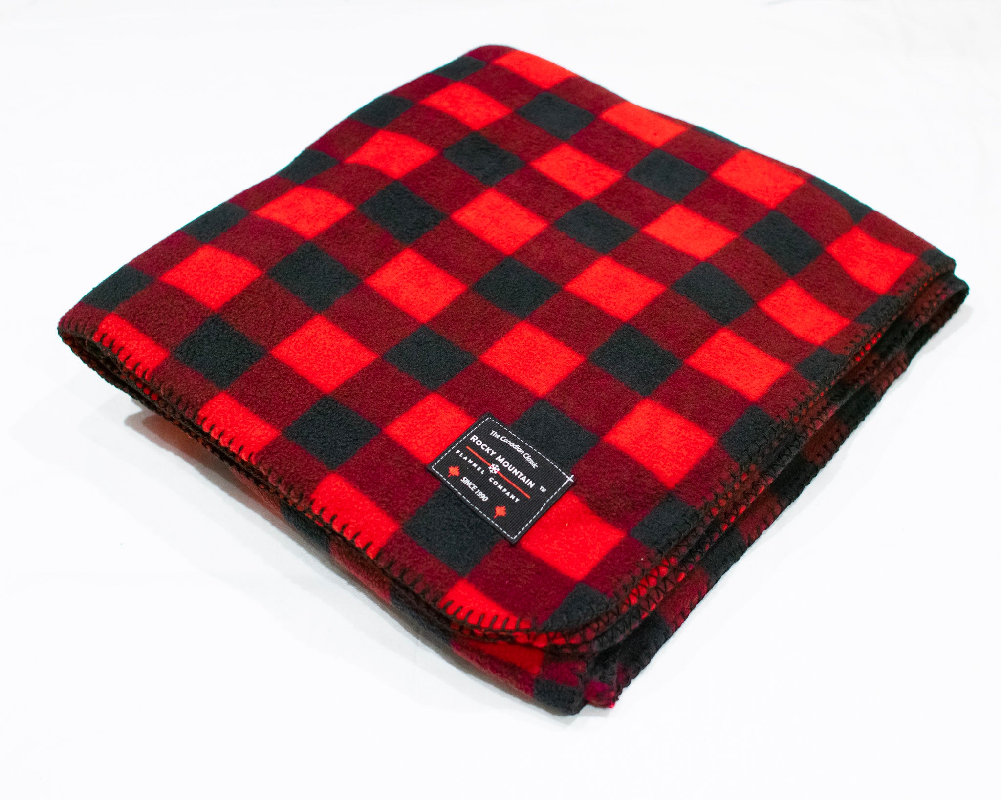 A red and black buffalo check fleece blanket with a label showing the brand name.