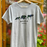 Grey t-shirt with bear and moose graphic and 'Banff Canada' text on a hanger against a blurred floral background.