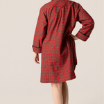 Woman wearing a red plaid nightshirt against a beige background