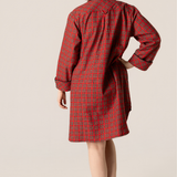 Woman wearing a red plaid nightshirt against a beige background