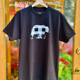 Black t-shirt with a white bear graphic on a hanger in front of a glass door.