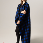 Person wearing a blue and black buffalo check blanket with 'Made in Canada' label on a plain background