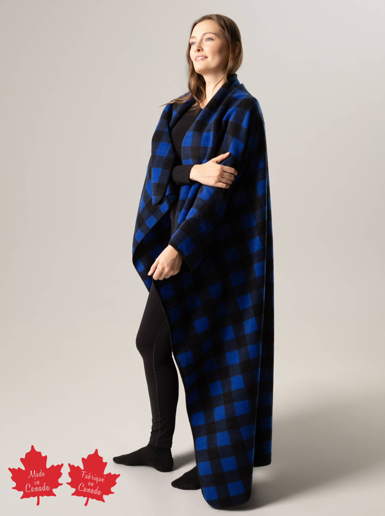 Person wearing a blue and black buffalo check blanket with 'Made in Canada' label on a plain background