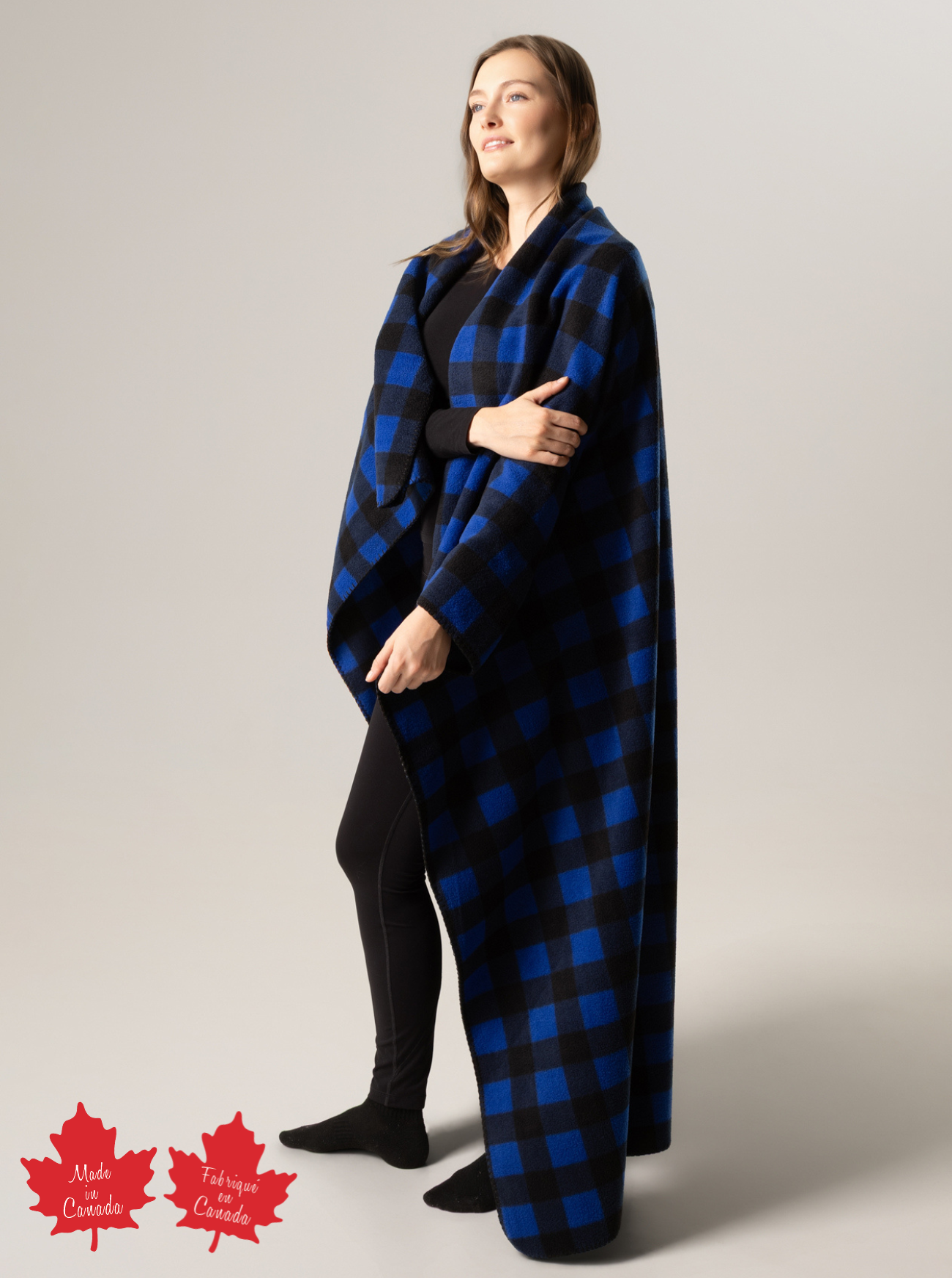 Person wearing a blue and black buffalo check blanket with 'Made in Canada' label on a plain background
