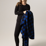 Woman holding a blue and black buffalo check blanket against a plain background
