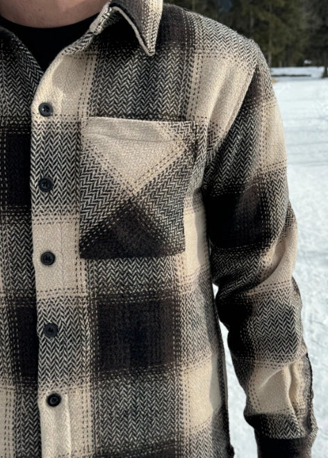 Close up of single breast pocket and brown herringbone weave.