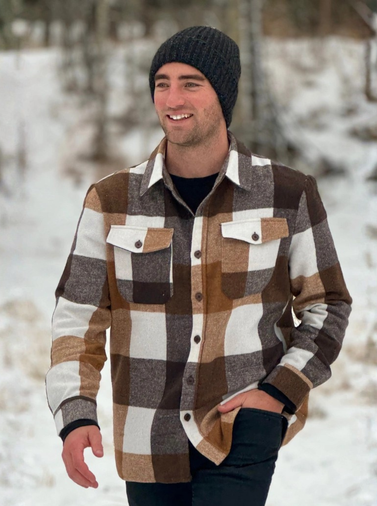 Man wearing a plaid flannel shacket and beanie in a snowy landscape in Banff, Canada