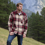 Man standing in a field, with mountains in the background.