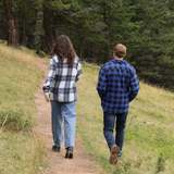 A man wearing a royal blue and black buffalo check padded flannel camping outdoor jacket with jeans.