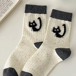 White socks with black cat designs and gray toes on a light surface.