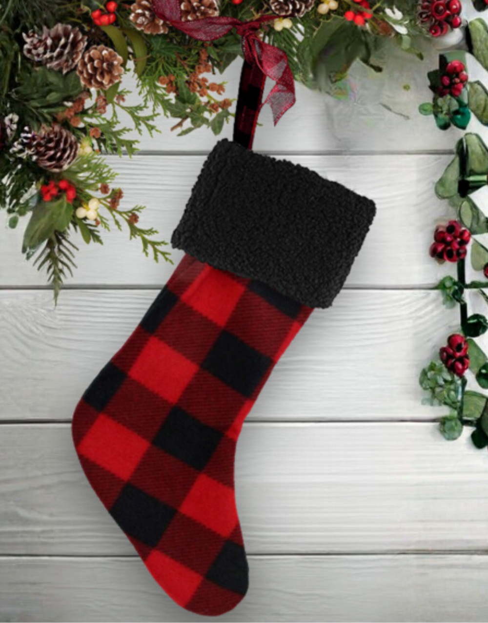 Red and black checkered Christmas stocking with greenery on a wooden background