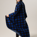Person wearing a blue and black buffalo check blanket draped over their shoulders on a plain background