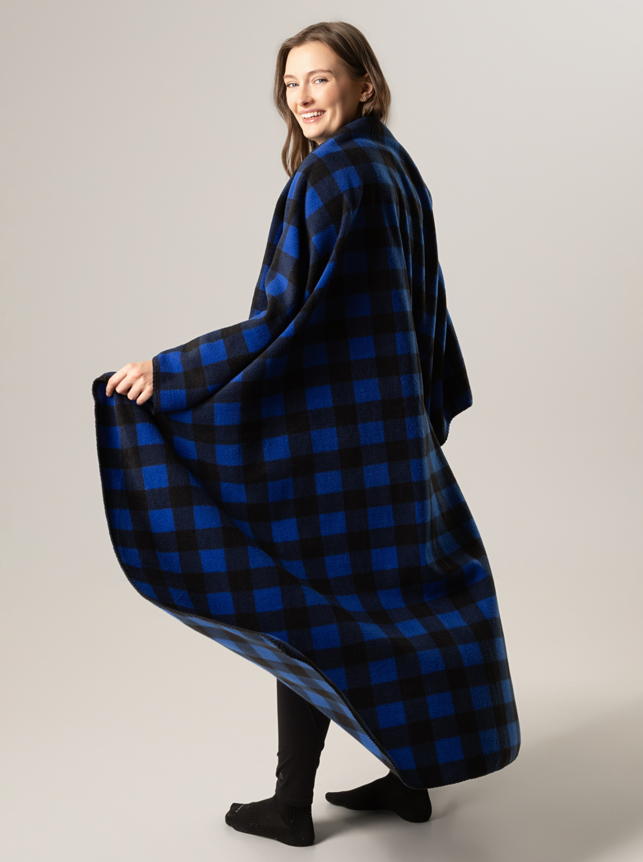 Person wearing a blue and black buffalo check blanket draped over their shoulders on a plain background