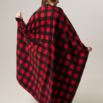 Person wearing a classic canadian red and black checkered blanket draped over them on a plain background