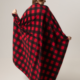 Person wearing a classic canadian red and black checkered blanket draped over them on a plain background