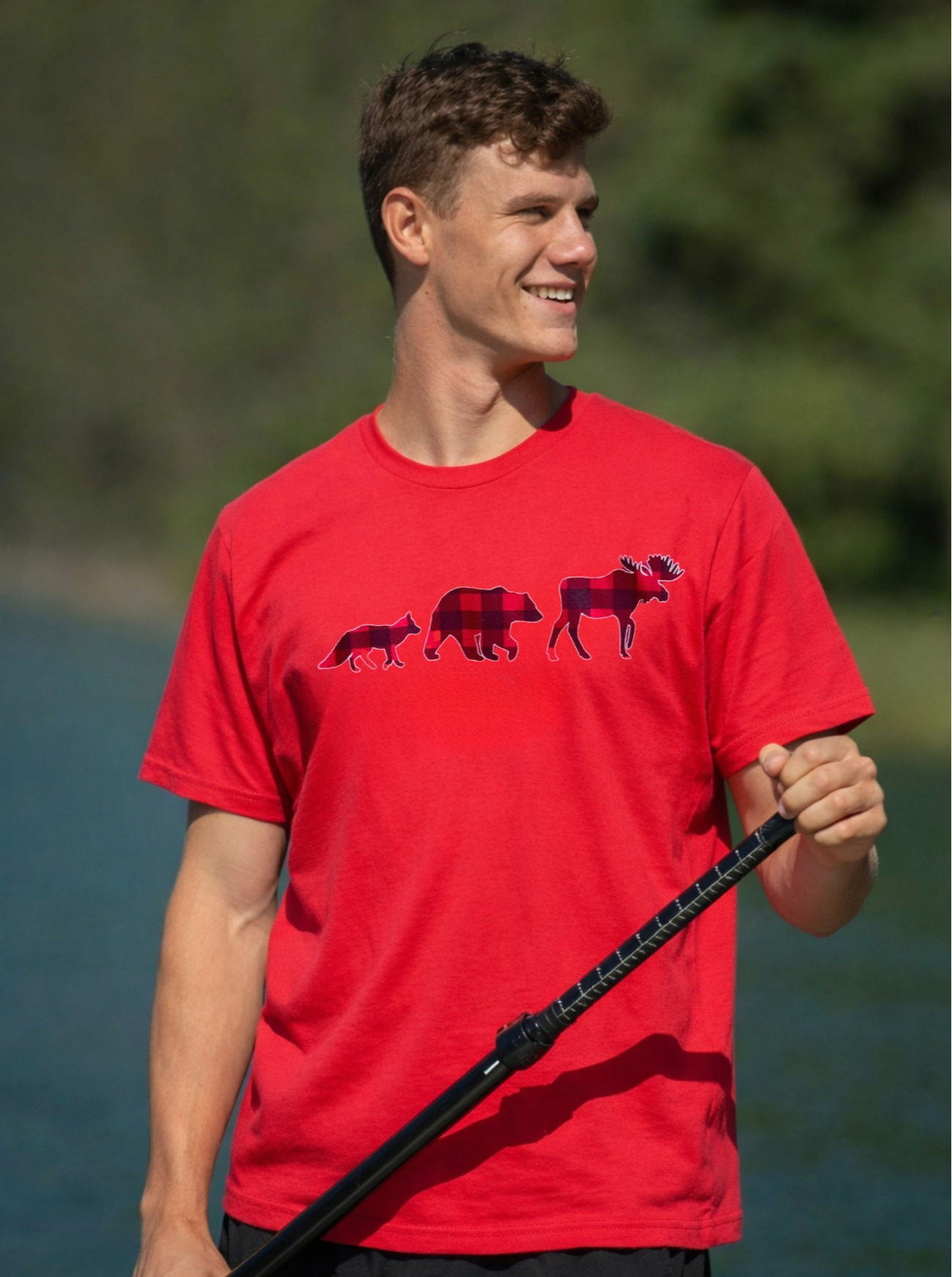 Man wearing a red t-shirt with bear graphics by a body of water