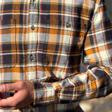 Close-up of a person wearing a plaid flannel shirt with a blurred background