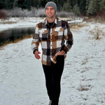 Man walking in the snow wearing our cozy flannel shacket in camel squares in Banff, Canada.