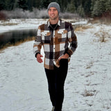 Man walking in the snow wearing our cozy flannel shacket in camel squares in Banff, Canada.