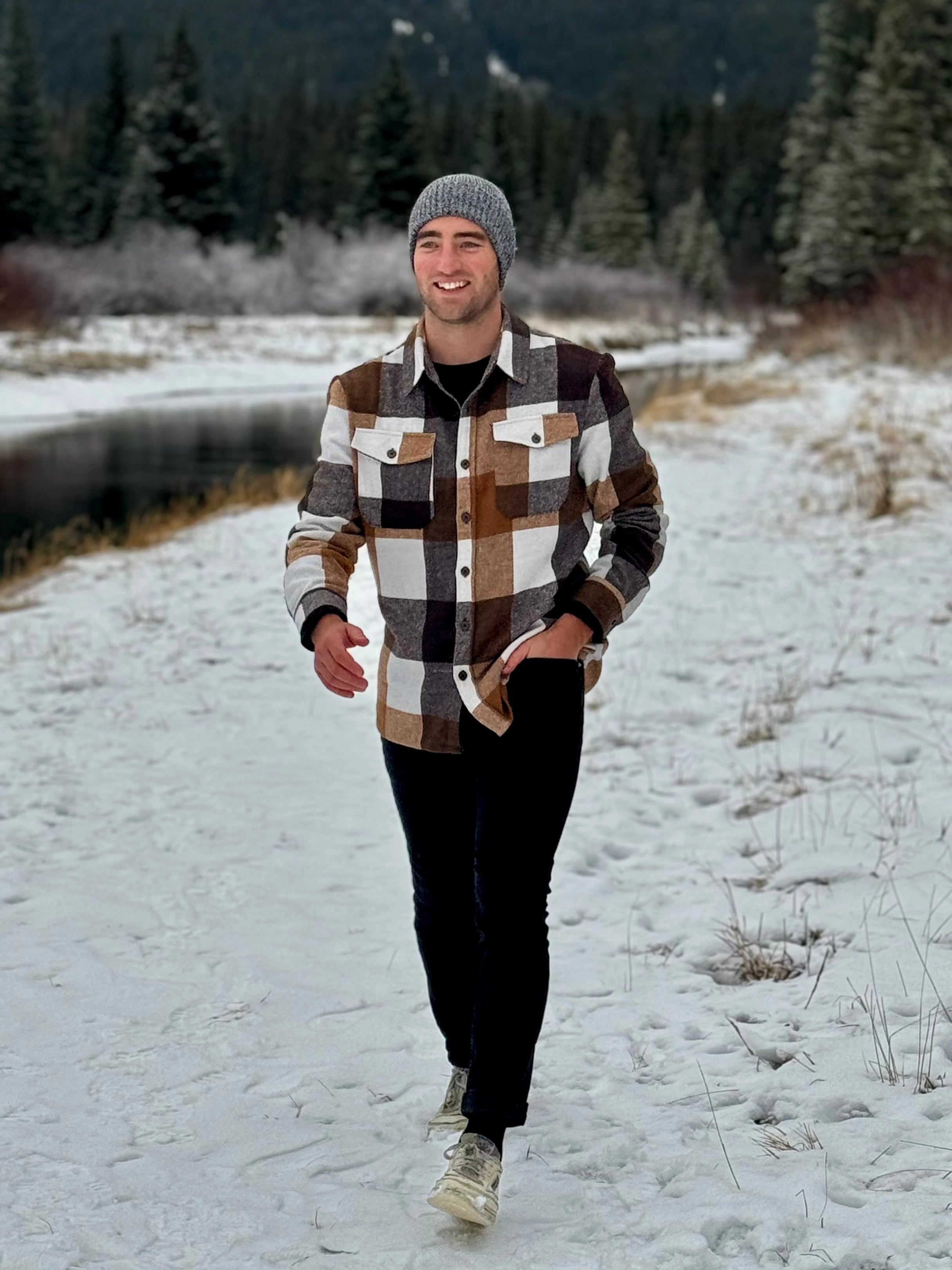 Man walking in the snow wearing our cozy flannel shacket in camel squares in Banff, Canada.