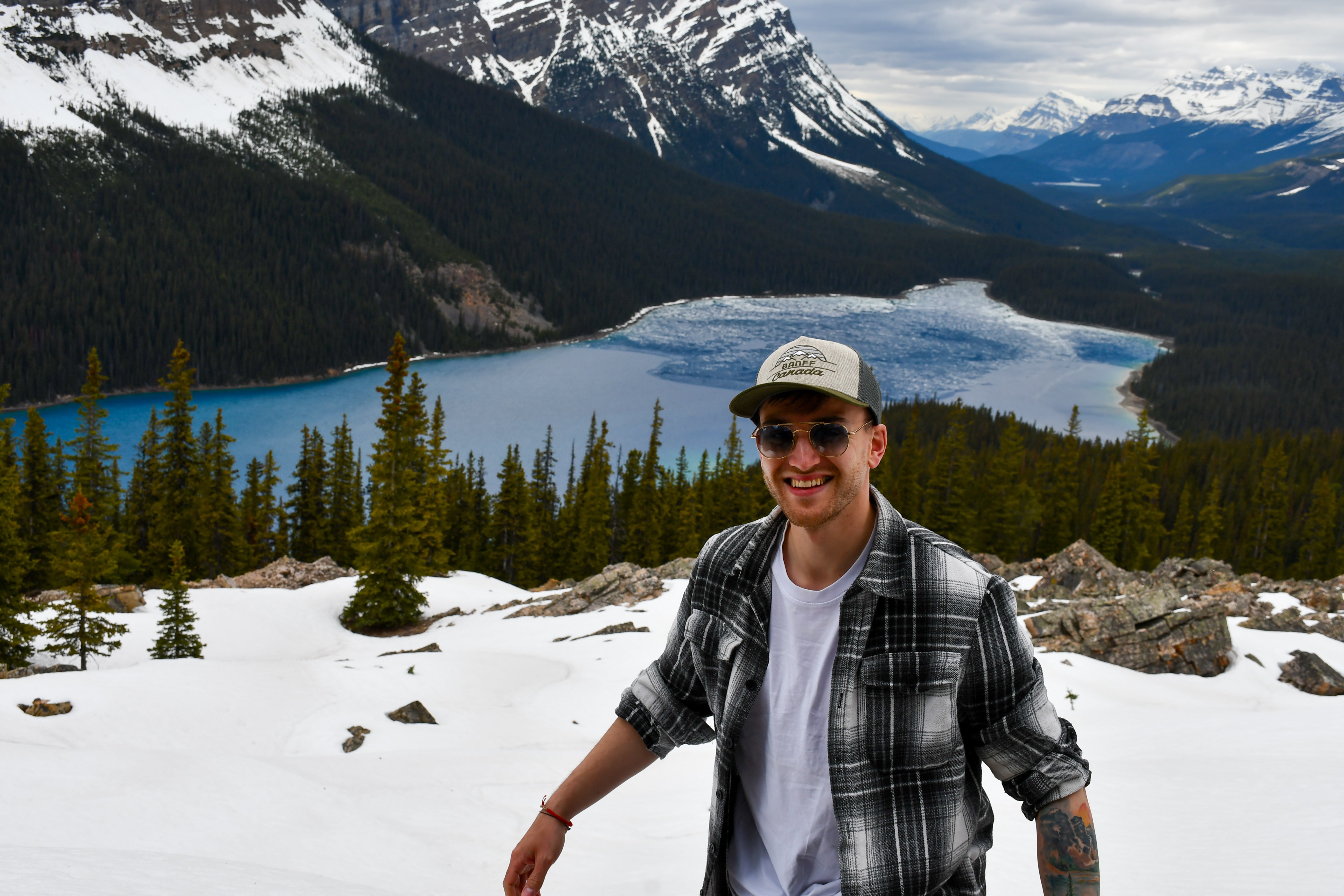 Person standing in a snowy landscape with a lake and mountains in the background