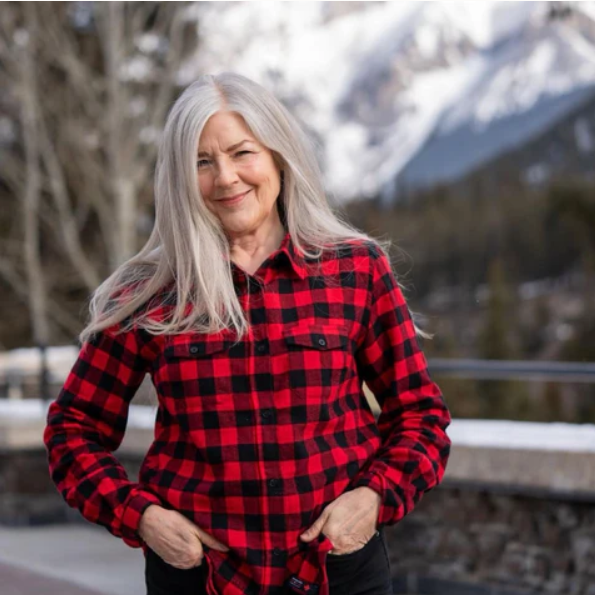 Woman wearing a red and black plaid shirt with a mountainous background