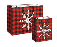 Two red and black plaid gift bags with white snowflake designs on a white background