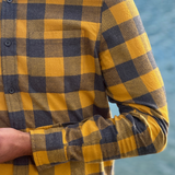 Gold and grey checkered shirt worn by a person with a blurred natural background