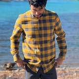 Man wearing a gold and grey buffalo check shirt by a river in Banff National Park