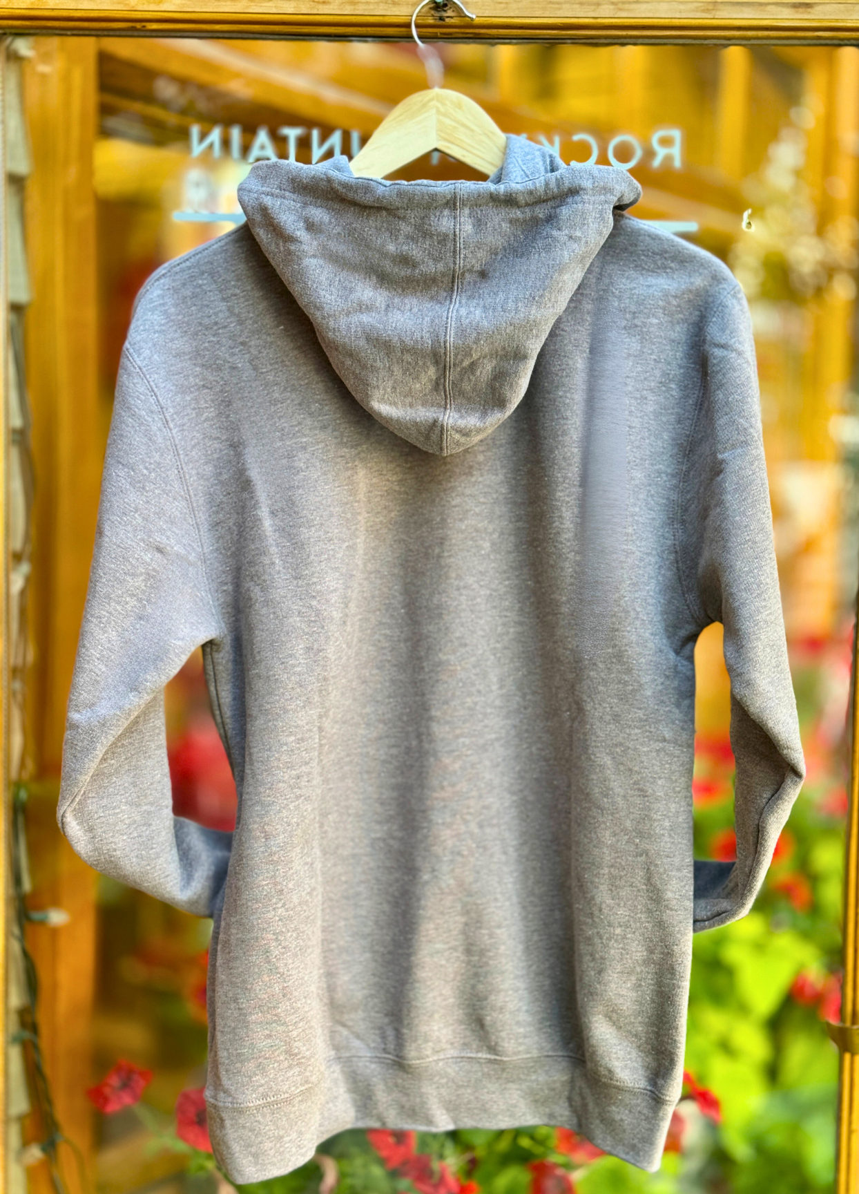 Grey hoodie with a hood on a hanger against a blurred background