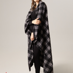 Woman wearing a black and grey checkered blanket with 'Made in Canada' label on a plain background