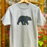 Grey t-shirt with a black watch bear graphic on a hanger against a blurred floral background