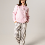 Woman wearing a pink hoodie and checkered pants on a plain background