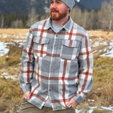 Man wearing a plaid flannel shirt and beanie standing in a snowy landscape in Banff, Canada