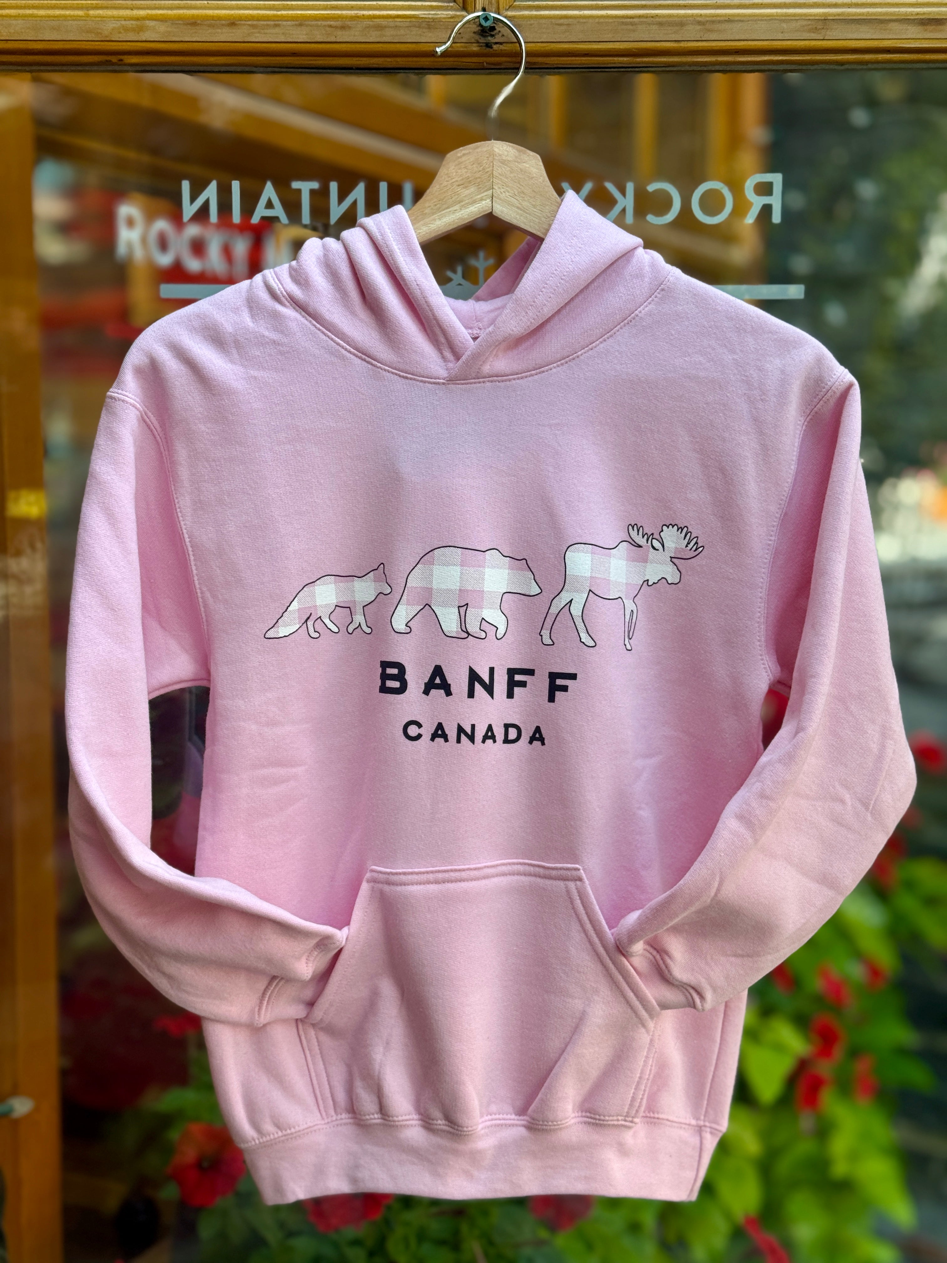 Kids Baby pink hoodie with animal graphics and 'Banff Canada' text on a hanger.